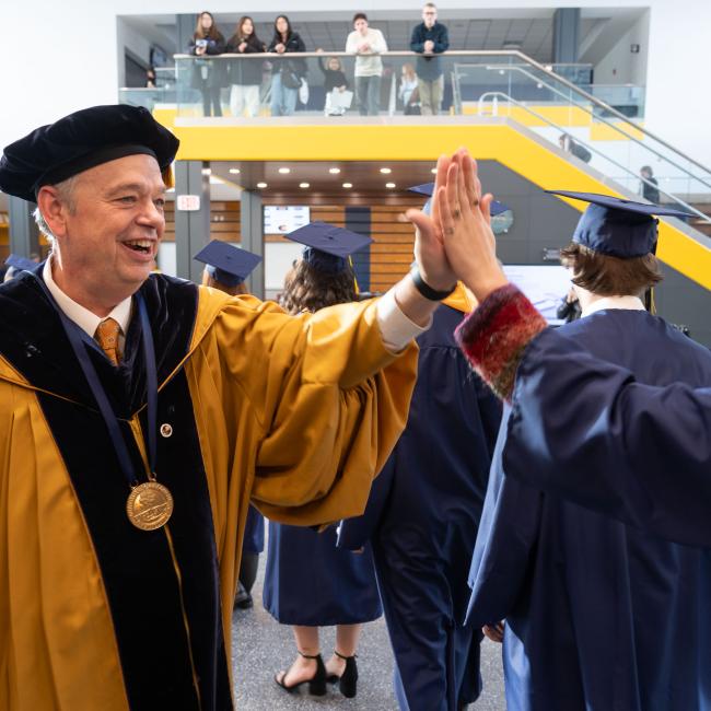 chancellor high five with student entering commencement 