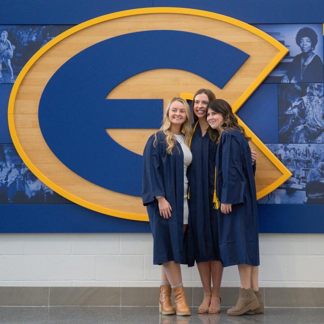 three friend posing for grad picture in front of E logo in Sonnentag 