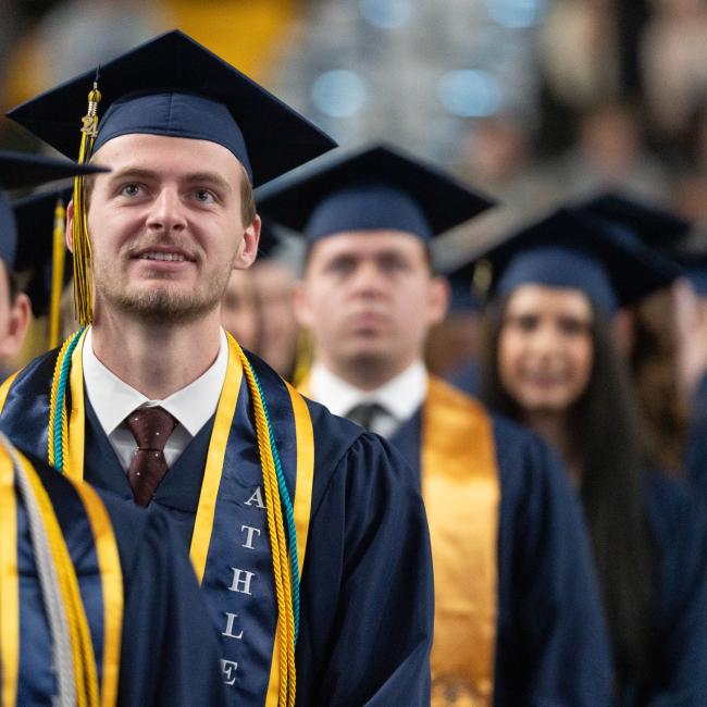 row of graduates in caps and gowns looking forward as entering 