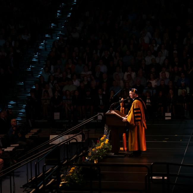 The Chancellor speaks at the podium on stage at commencement
