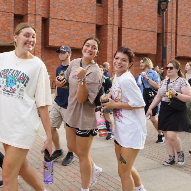 Four students smile at camera while walking across campus during Blugold Welcome week.