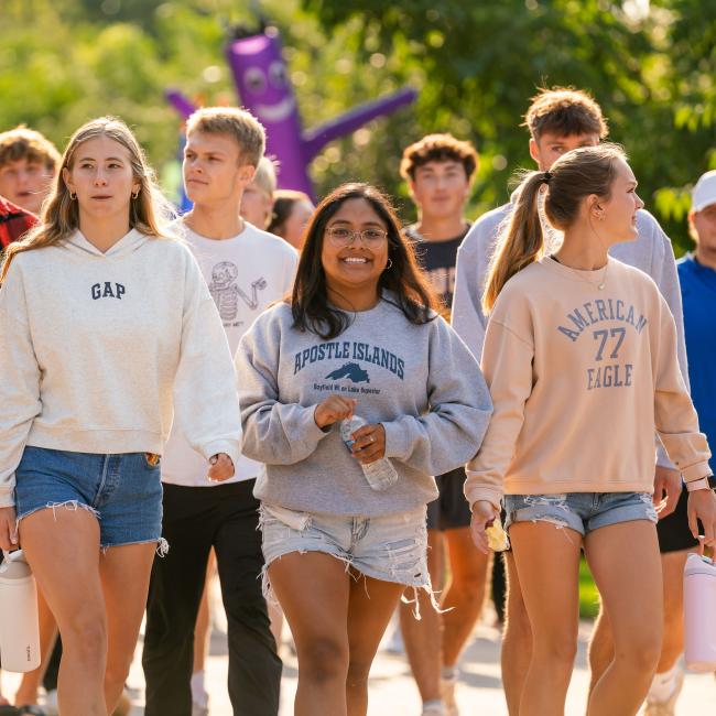 A group of students walk together outside on campus during Welcome Week.
