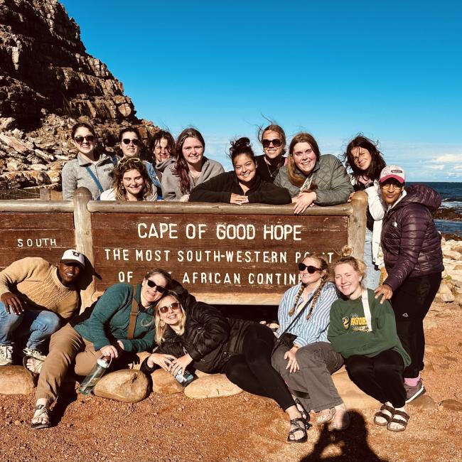 Students pose in front of a sign that reads "Cape of Good Hope"