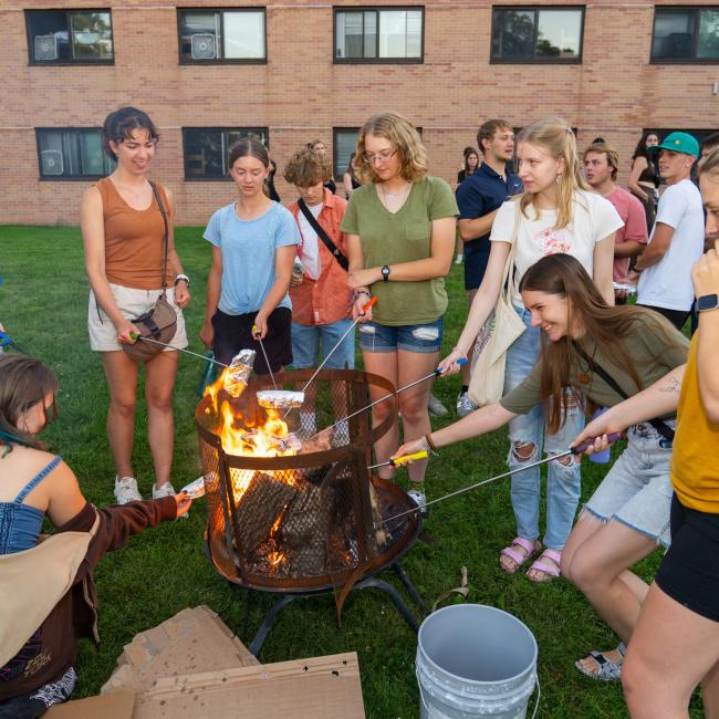 Group of students gathered around a campfire.