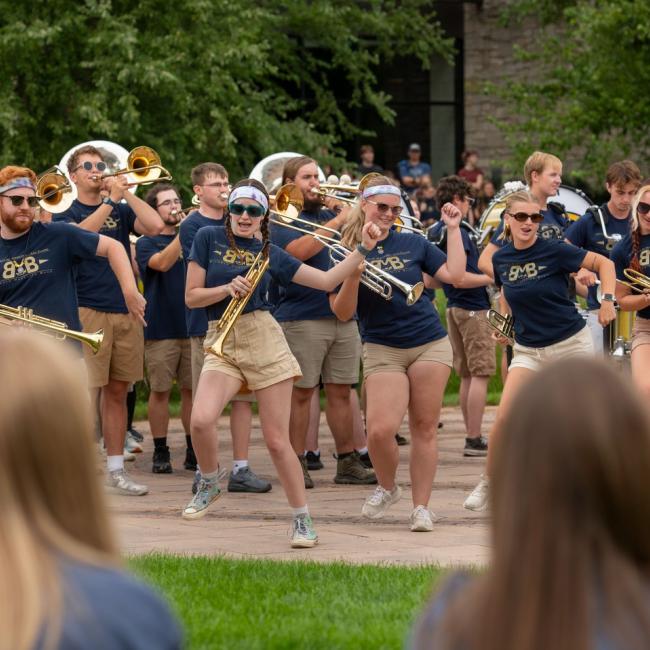 A group of Blugold Marching Band students play in front of a crowd on Opening Day. 