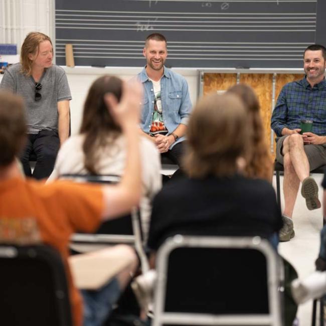 Students laugh and raise their hands during a presentation with UWEC alums.