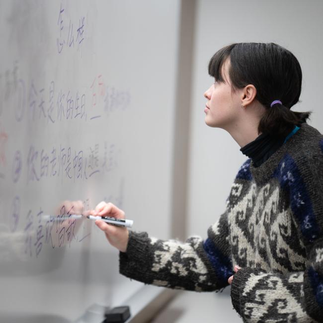 A student writes Chinese characters on a whiteboard