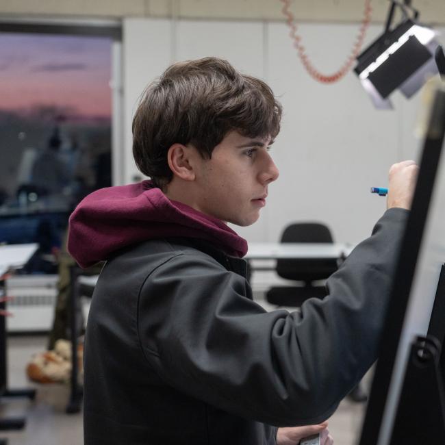 A student draws on a canvas during an Art class. 