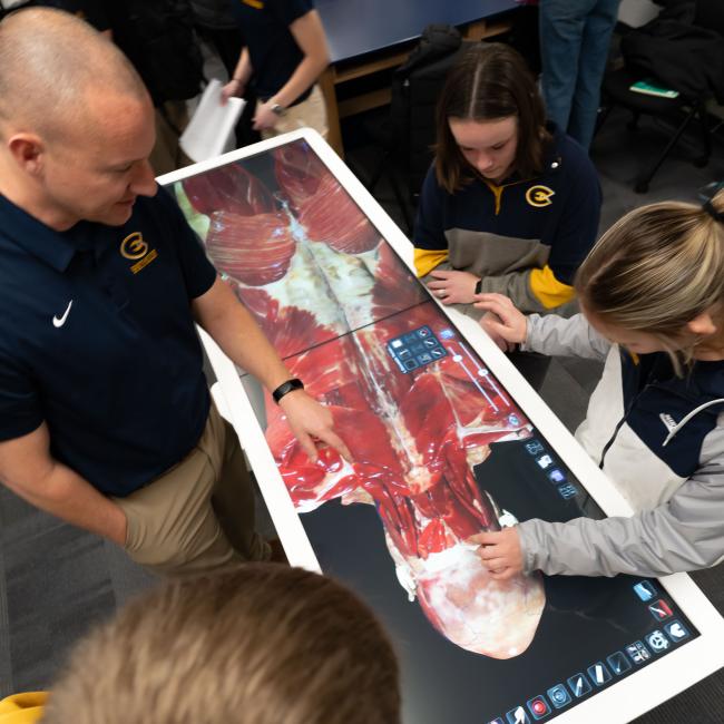 Students work on the anatomage table alongside a faculty member.