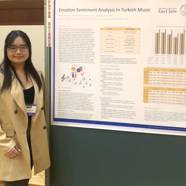 Honors student Nguyen Nguyen stands in front of a poster presentation