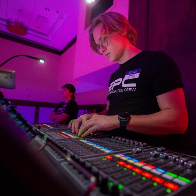 Students work the sound board and lighting during a concert.