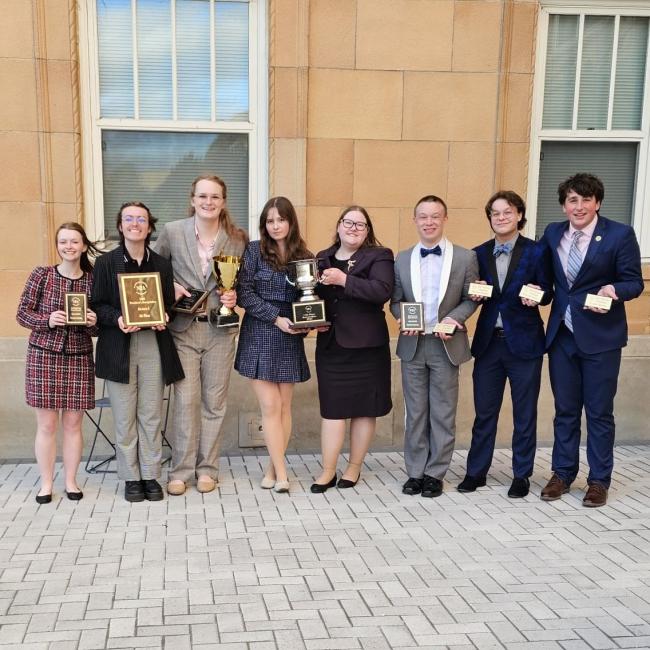Clemen and the UWEC forensics team holding their competition spoils