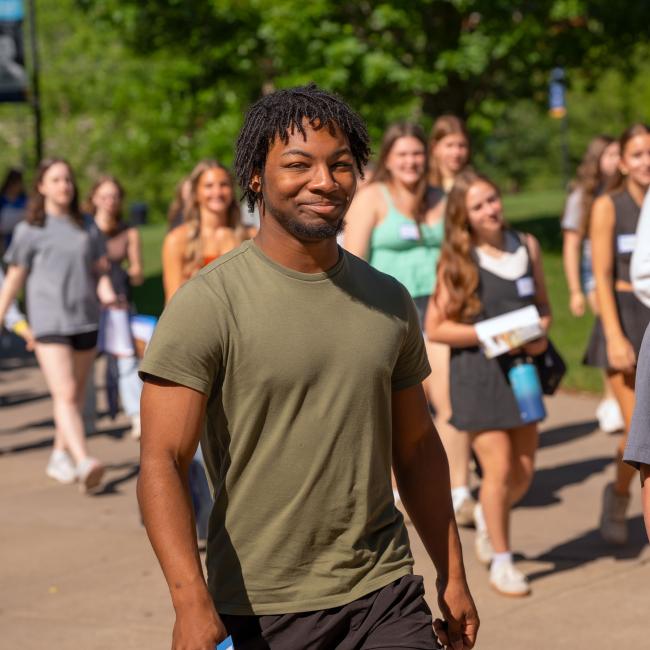 Students smile at the camera as they walk around campus during Orientation.