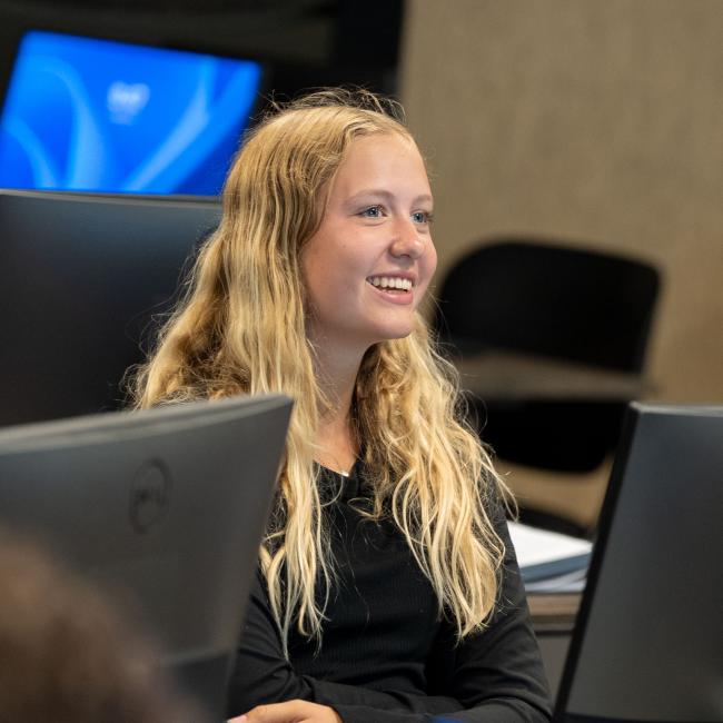 A student smiles as she works on a computer during Orientation.