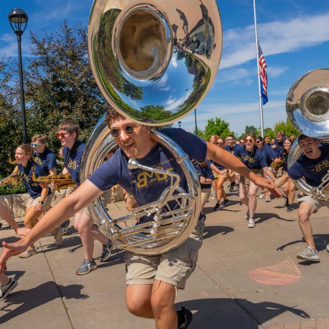 A fun shot of Blugold Marching Band members dancing and playing their instruments.