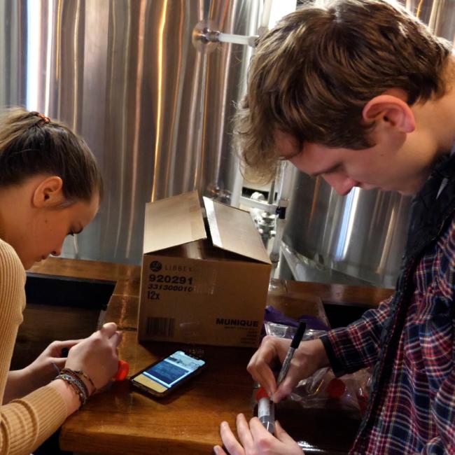 two students in local brewery labeling beer samples for testing