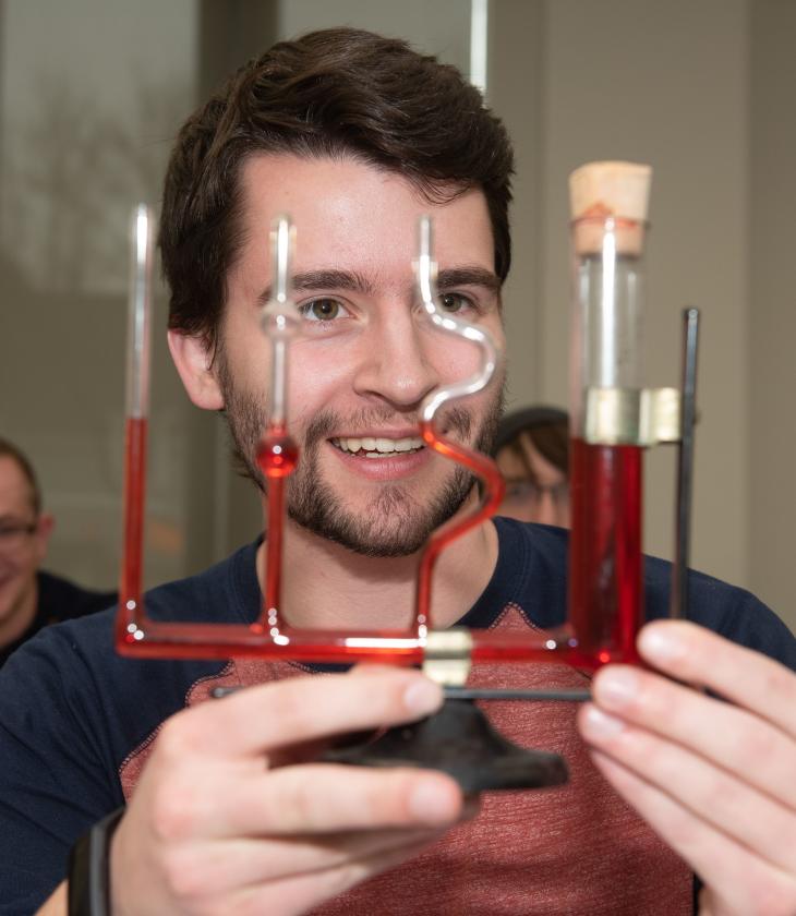 Physics student holding a water filled pressure instrument 