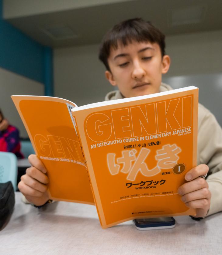 student holding textbook in Japanese language class