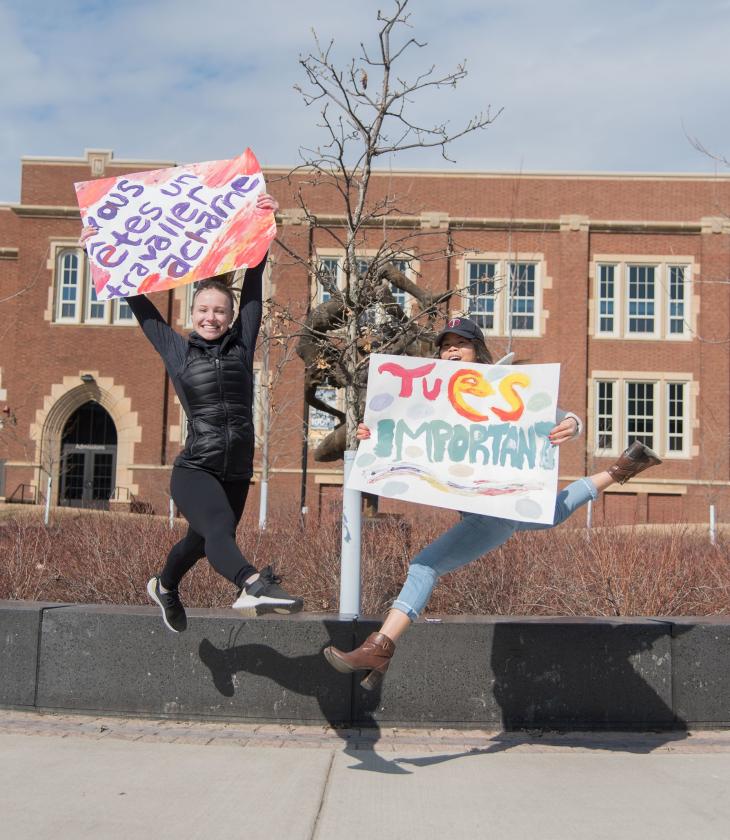 French students jumping by Sprites with signs in French
