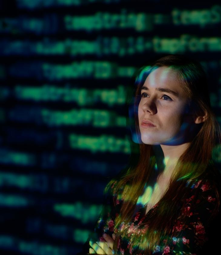 student in front of a screen of data