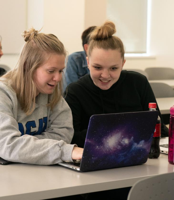two students in classroom on laptops