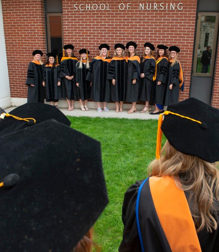Nursing DNP grads 2022 outside CONHS in gowns and hoods