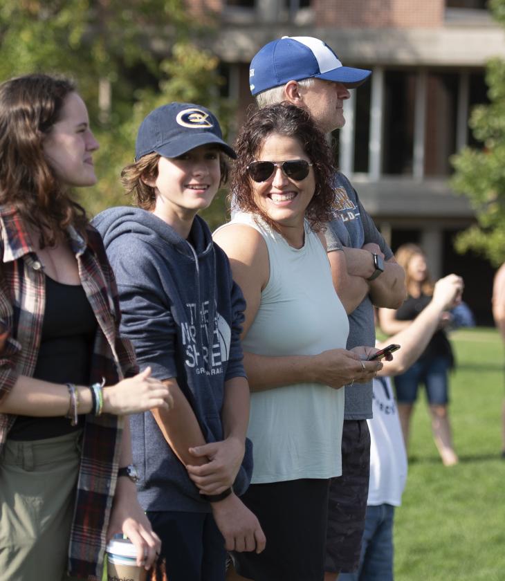 Student and parents laughing outdoors at a campus event