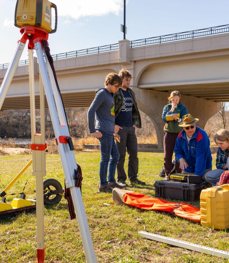 geogrpahy students mapping on the river bank by footbridge