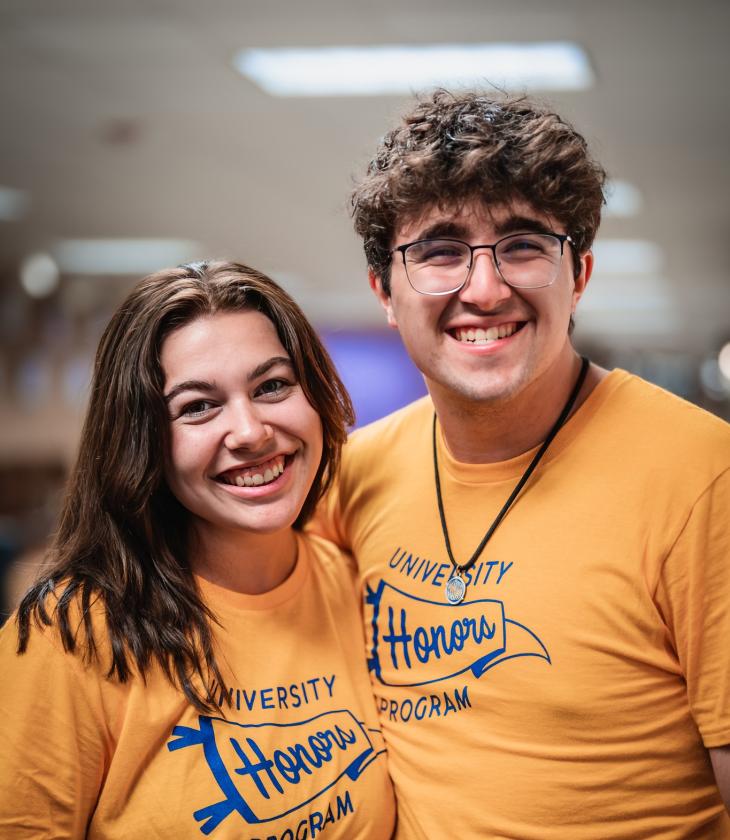 two students wearing gold University Honors Program t-shirts 