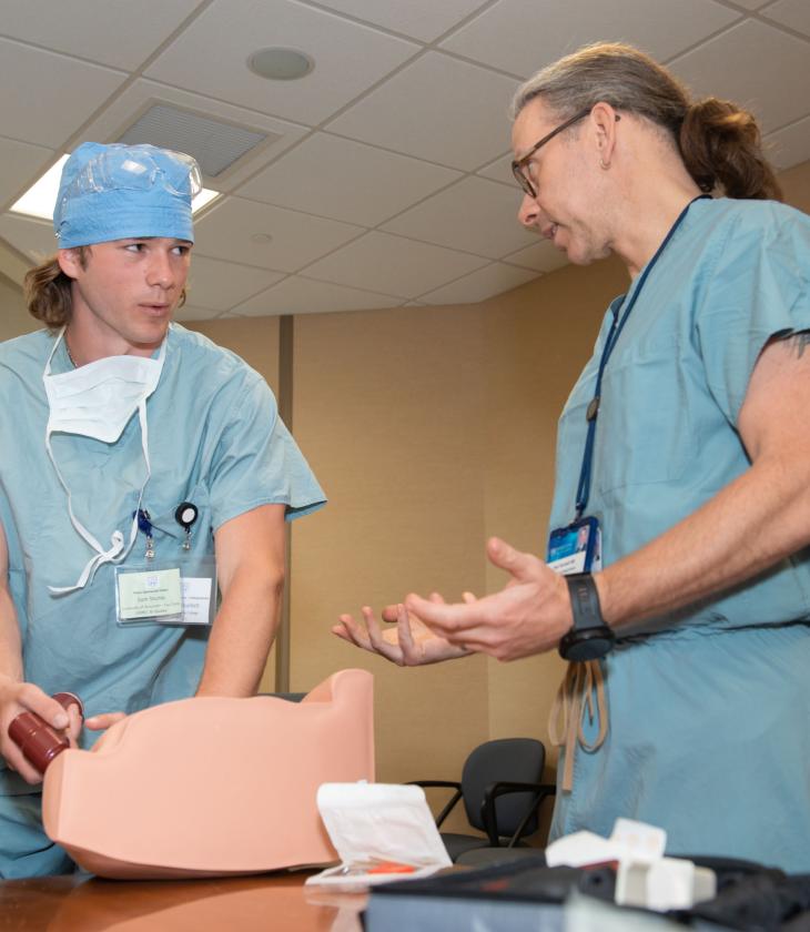 A student works on a simulation with a Mayo Clinic physician, both wearing scrubs.