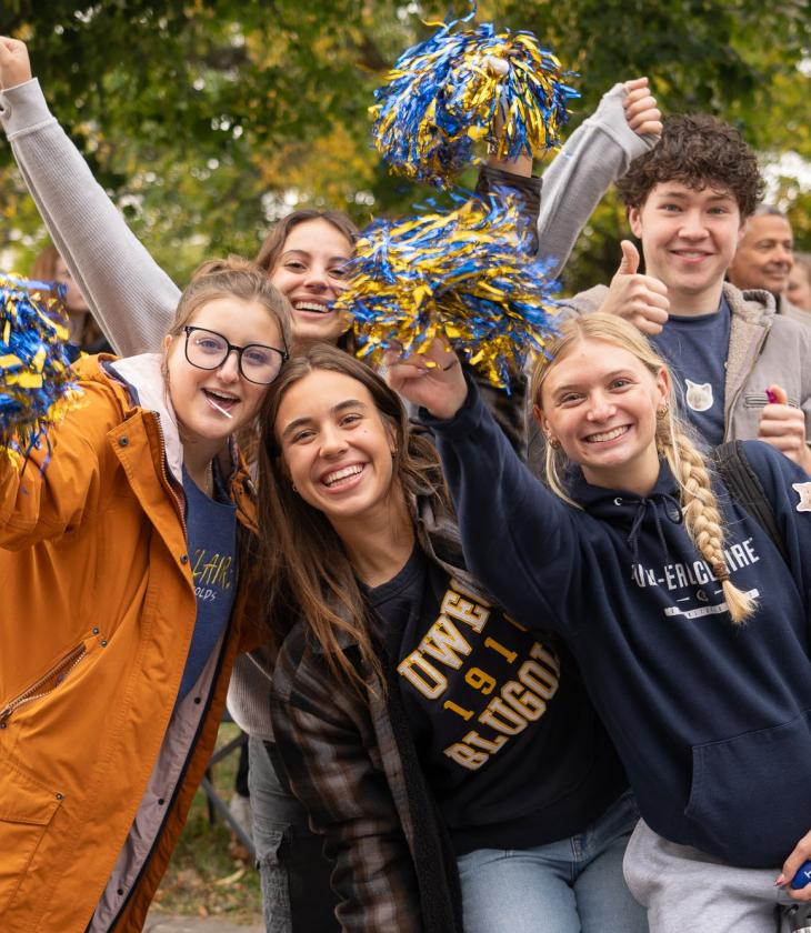 Students cheering with pom poms at homecoming parade.