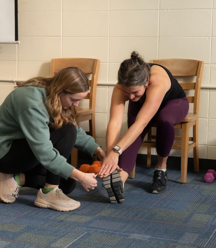 Student helps a client participating in the Community Fitness Program stretch.