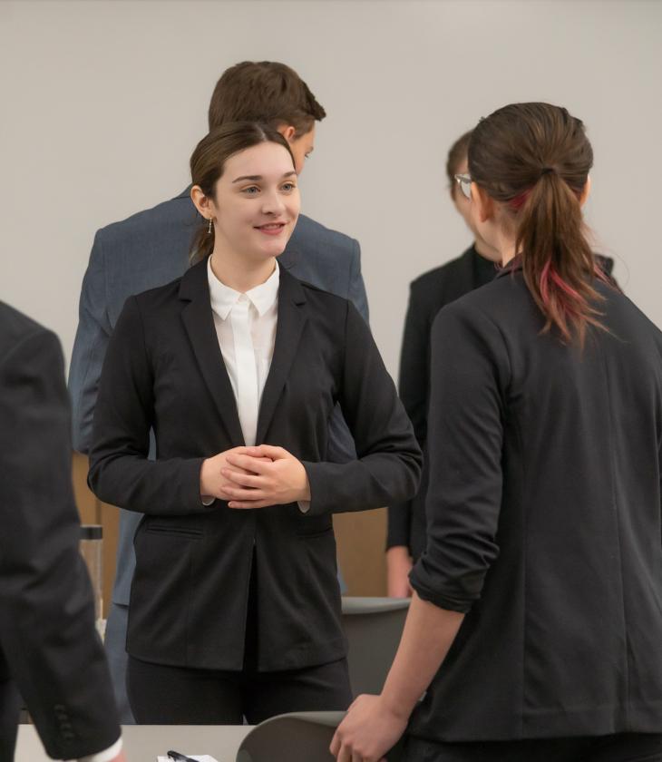 Woman wearing a black suit speaks with another woman