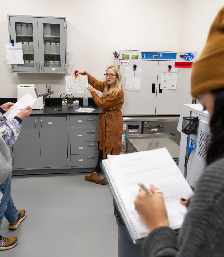 Student writes on a notepad during a lab visit for the Environmental Public Health program.