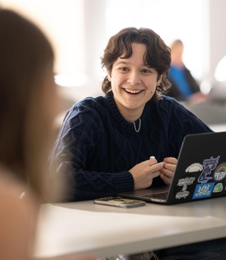Student smiles at another student in a classroom