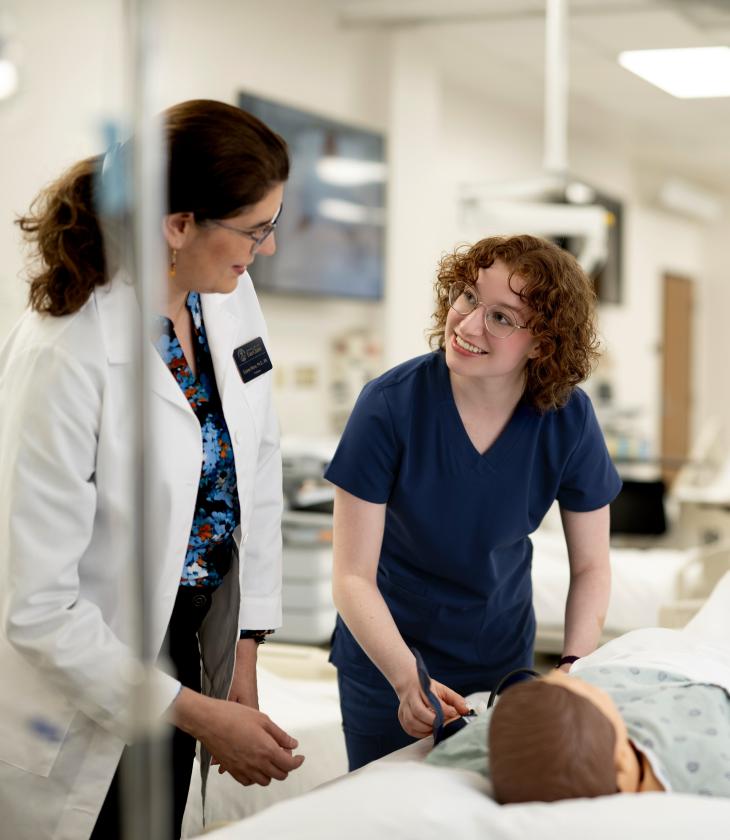 A Nursing student and professor work together over a manequin.