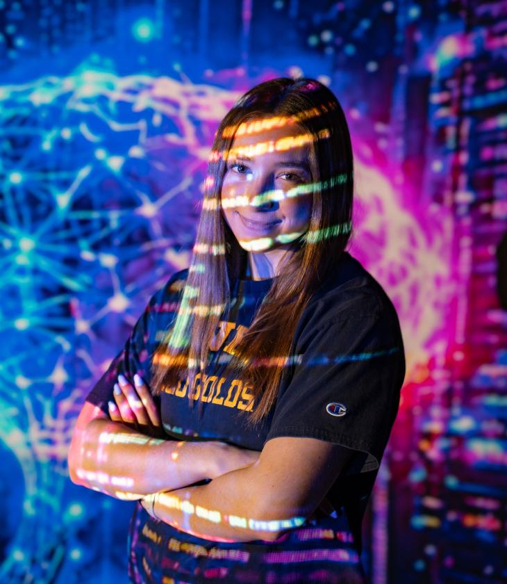 Artificial intelligence major poses in front of digital screen