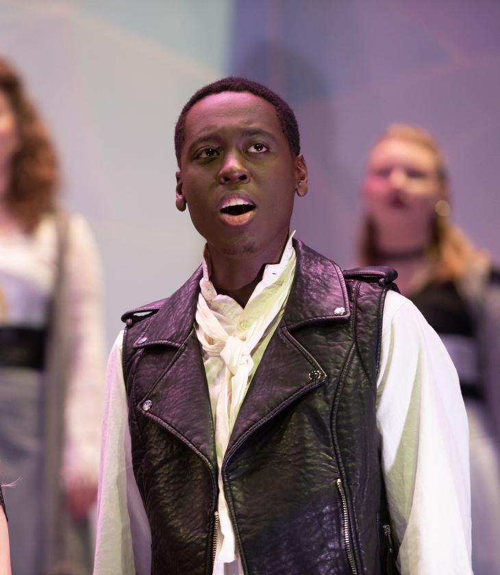 A group of students sing on stage during a performance