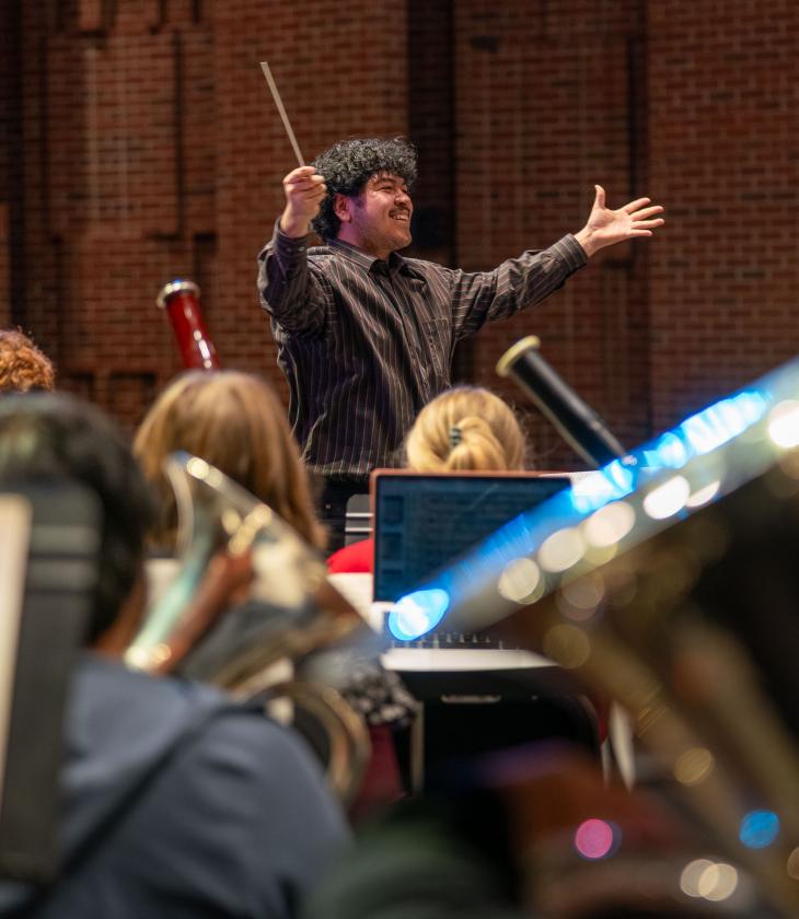 A conductor enthusiastically guides a musical group during a performance