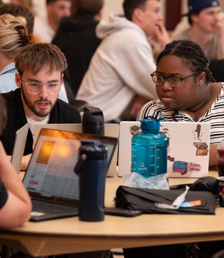 Students look at a laptop while gathered for the College of Business SIM Super Bowl