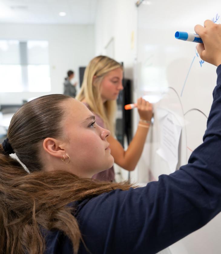 A student writes on a white board during Orientation.
