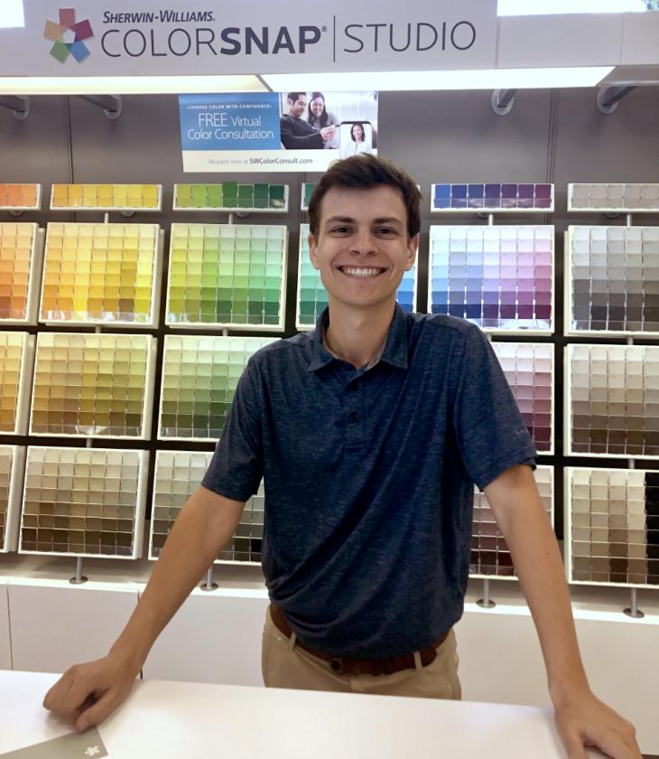 male student standing at counter in paint store