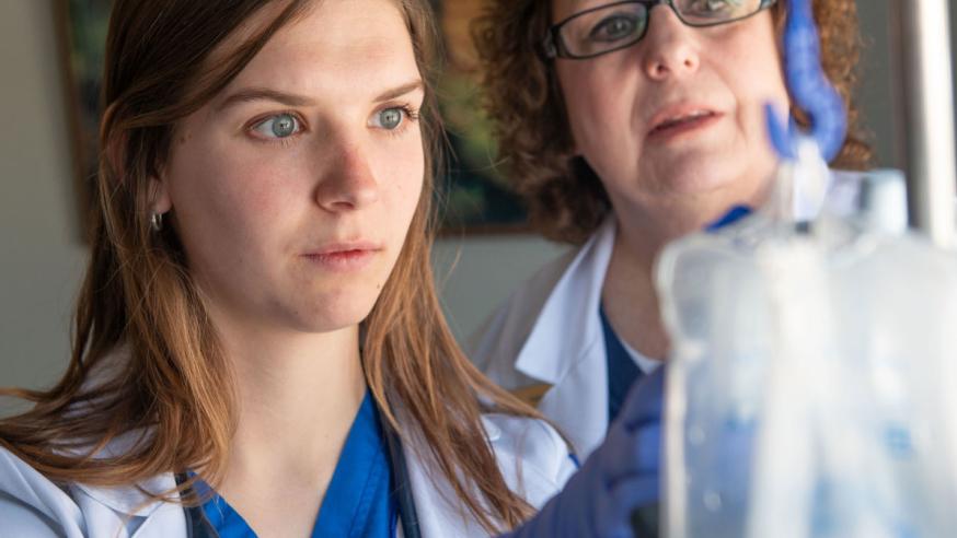Two students in lab coats doing an experiment