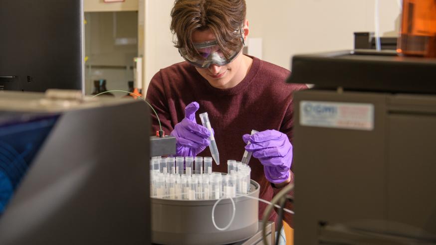 chemistry student placing tubes in device 