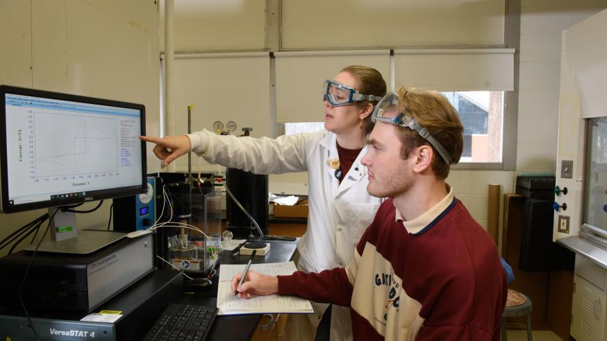 student and faculty analyzing chemistry data in lab 