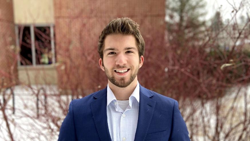 male student, Wyatt Anklam, in a suit outside Schneider Hall
