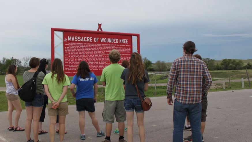 students standing in front of signage at Wuonded Knee while on a SD immersion