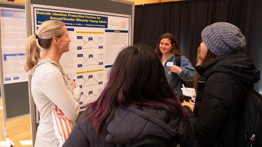 students and faculty at psychology event by  a research poster