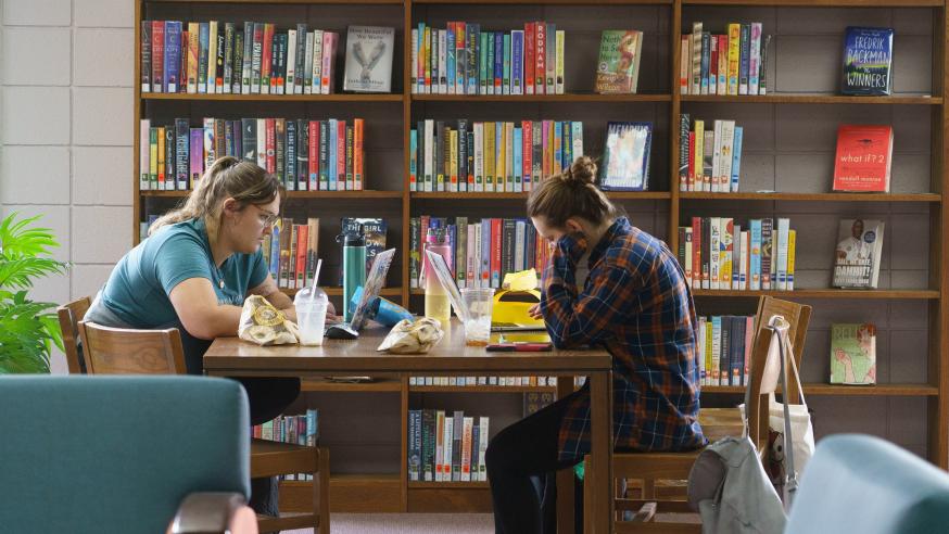 two students studying at a library table