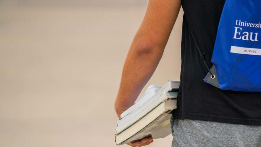 student walking away from camera holding stack of books